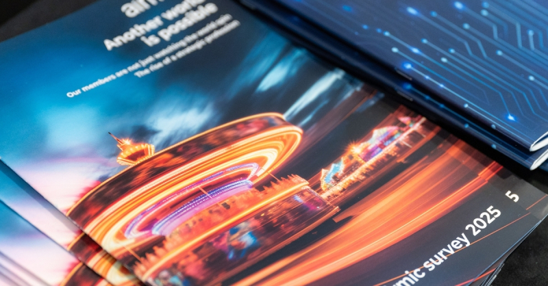 A stack of printed copies of the report, the front cover, a timelapse photograph of a brightly lit merry-go-round at night.